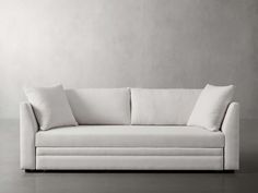 a white couch sitting on top of a hard wood floor next to a gray wall