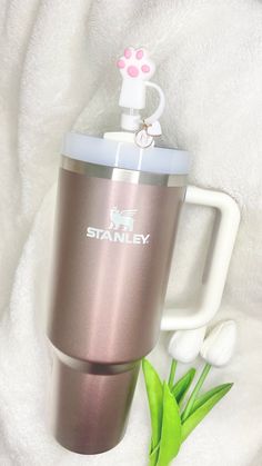 a stainless steel travel mug with a handle and flower on the side next to it