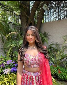 a woman in a red and pink lehenga