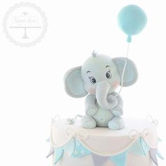 an elephant figurine sitting on top of a cake with a balloon attached to it