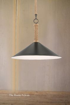 a black and white pendant light hanging from a wooden table with rope on the end