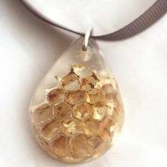 a close up view of a necklace with honeycombs in the shape of a tear