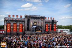 a large group of people standing in front of a stage with red and black doors