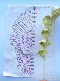 a crocheted flower is shown in front of a piece of paper with the pattern on it