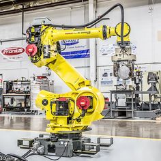 a yellow robot is sitting in a room with other machines and equipment on the floor