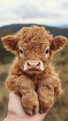 a small brown cow sitting on top of a person's hand