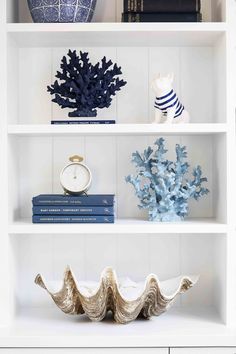 books, vases and other decorative items are displayed on the shelves in this white room