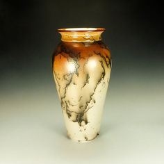 a brown and white vase sitting on top of a table