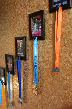 several medals are hanging on the wall in front of two framed pictures and one has a ribbon attached to it