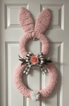 a pink bunny ears wreath hanging on the front door with a flower in it's center