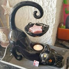 a black cat tea light holder with a pink candle