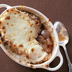 a casserole dish with meat and vegetables in it on a brown tablecloth