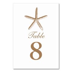 a table number with a starfish on it and the word table 8 written in brown ink