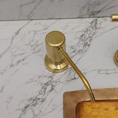 a bathroom sink with gold faucet and soap dispenser