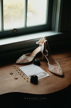 a pair of shoes sitting on top of a wooden table next to a notepad