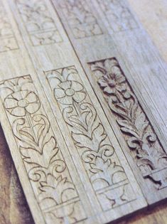 carved wood panels with designs on them sitting on top of a wooden table next to a cell phone