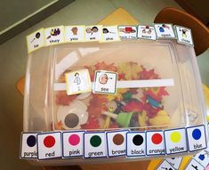 a plastic container filled with lots of different colored candies next to matching cards for sight words