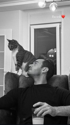 a black and white photo of a man sitting on a couch with a cat in the background