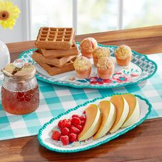 two plates with waffles, apples and raspberries are on the table