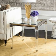 a living room with two white chairs and a glass table in front of the couch