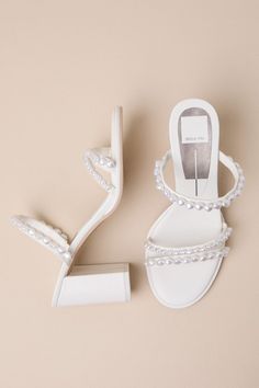 Everyone will be swooning over your look when you step out in the Dolce Vita Barrit Pearl Vanilla Embellished Strappy High Heel Sandals! Smooth faux leather shapes these stunning heels with an almond footbed and two slender toe straps, followed by a matching vamp strap, all embellished with organically-shaped faux pearls in varying sizes. The simple slide-on design makes for effortless on-and-off, while a snake-embossed block heel completes the look! 3. 25" wrapped block heel. Lightly cushioned Simple Sandals Heels, Summer Pearl Embellished Block Heel Heels, Chic Low Heel Pearls Embellished Heels, Leather Embellished Low Heel Sandals, Chic Embellished Sandals With Single Toe Strap, Leather Sandals With Sculpted Heel For Wedding, Pearl Embellished Low Heels For Summer, Chic Open Heel Pearls Heels, Spring Pearl Embellished Open Heel Shoes