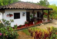 a small white house with red hearts on the windows and plants in front of it