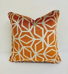 an orange and white decorative pillow on a white background with silver lines in the middle