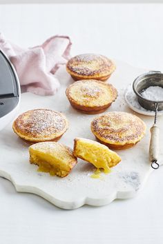 several pastries on a white tray next to an electric food slicer and measuring spoon