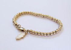 "Simple. Chic. Minimalist™ Super cute beaded bracelet for your little daughter. Also a great gift! Tiny 14k gold filled beads (3mm) and a stunning 14K gold plated Hamsa Hand charm are strung on a sturdy 14K gold filled Rollo (superb quality) chain. Bracelet available in the following sizes: 4\"-4.5\" (4\" with half-an-inch of extension chain) 0-1 years old 4.5\"-5\" (4.5\" with half-an-inch of extension chain) 1-2 years old 5\"-5.5\" (5\" with half-an-inch of extension chain) 2-5 years old 5.5\" Gold Beads Bracelet, Girl Bracelet, Hamsa Bracelet, Baby Bracelet, Gold Bead Bracelets, Simple Chic, Baptism Gifts, Hamsa Hand