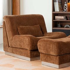 a chair and ottoman in a living room with bookshelf behind it on the floor