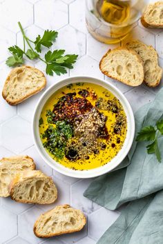 a bowl of soup with bread and parsley on the side