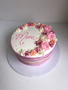 a white cake with pink flowers and the word mom on it