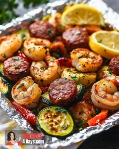 shrimp, zucchini, and sausage on foil with lemon wedged garnish