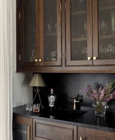 a kitchen with wooden cabinets and black counter tops, along with vases filled with flowers