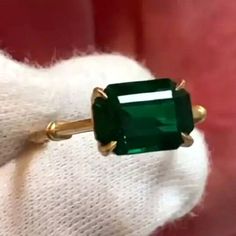 an emerald ring sitting on top of a white glove