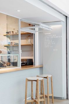 two stools in front of a window with writing on the wall behind them,