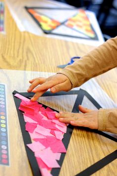 a child is cutting out pink and black paper