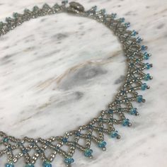 This beautiful seed bead choker was handmade by a friend and is perfect for everyday wear.  It features clear silver beads with blue and green accent beads.  the closure is a plastic silver button that slips though a loop on the other side.  From end bead to loop it measures 41 cm. If you are not sure if it will fit try using a string or ribbon around your neck to measure.