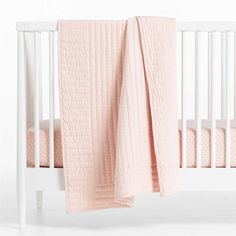 a crib with a pink blanket on top of it