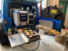 a blue truck parked inside of a garage next to other vehicles and food items on a table