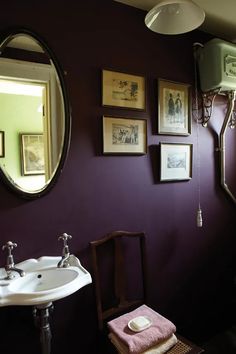 a bathroom with purple walls and pictures on the wall