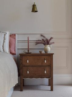 a bed room with a neatly made bed and a small wooden table next to it