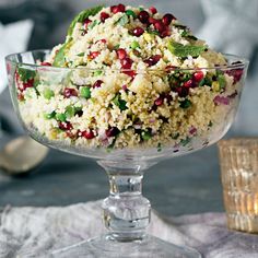 a bowl filled with rice and vegetables on top of a table next to a candle