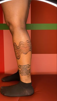 a person with a tattoo on their leg standing in front of a red and green wall