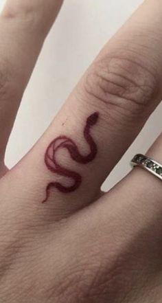 two people with tattoos on their hands and one has a snake tattoo on the ring finger