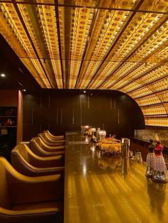 the interior of a restaurant with yellow lights on the ceiling and chairs in front of it