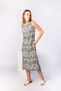 a woman standing in front of a white wall wearing a dress with flowers on it