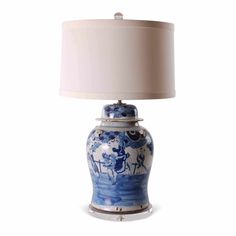 a blue and white table lamp with a shade on the top, sitting in front of a white background