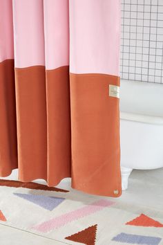 a pink and orange shower curtain in a bathroom next to a bathtub with a white toilet