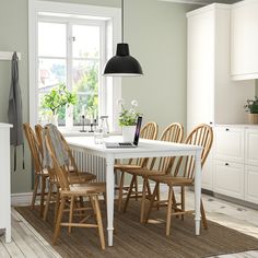 a dining room table with six chairs and a laptop on top of it, in front of a window